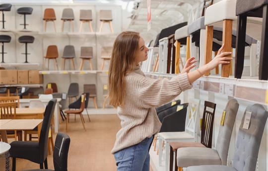 Young woman chooses furniture for her apartment in furniture store