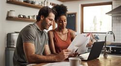 Cropped shot of a couple using their laptop and going through paperwork at home