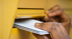 hand reaches into row of mailboxes for mail