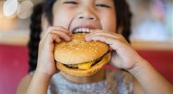 child eating cheeseburger in food court