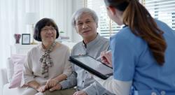 Young nurse holding a tablet and working as an in-home caregiver for a senior couple.