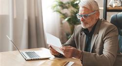 Attentive senior man sitting at a desk and looking at a document.