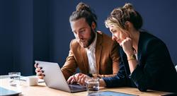 two marketers sharing a laptop