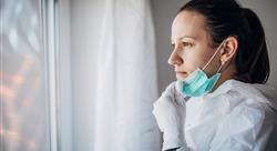 One woman, worried female doctor in protective suit, looking through the hospital window.